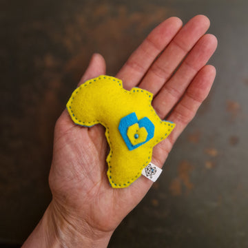 Yellow felt Africa-shaped magnet with a blue and yellow layered heart symbol.