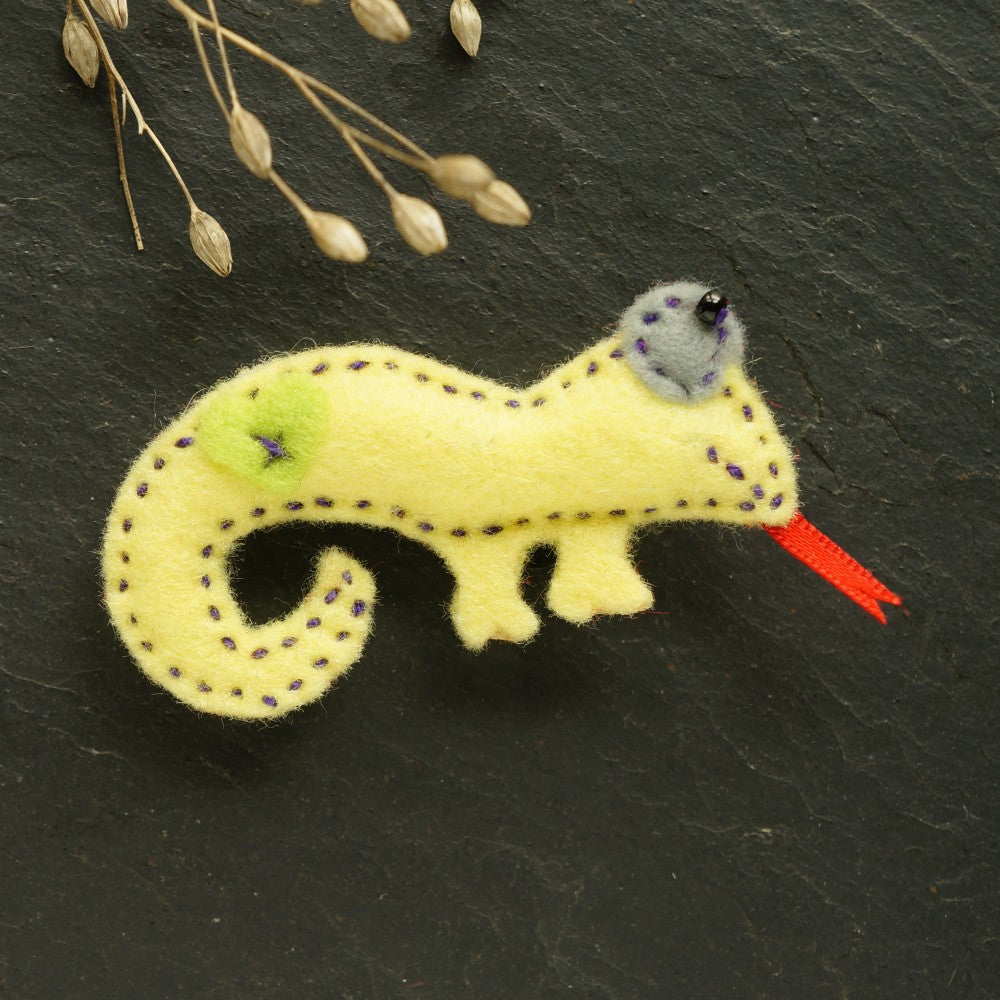 Hand-sewn yellow Chameleon Brooch with grey beaded eye and red tongue on dark background