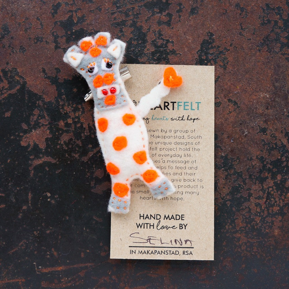Handmade felt white giraffe brooch with orange spots on a brown background