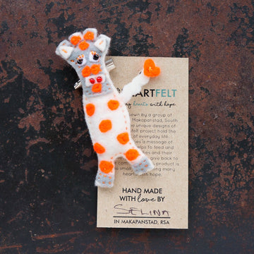 Handmade felt white giraffe brooch with orange spots on a brown background